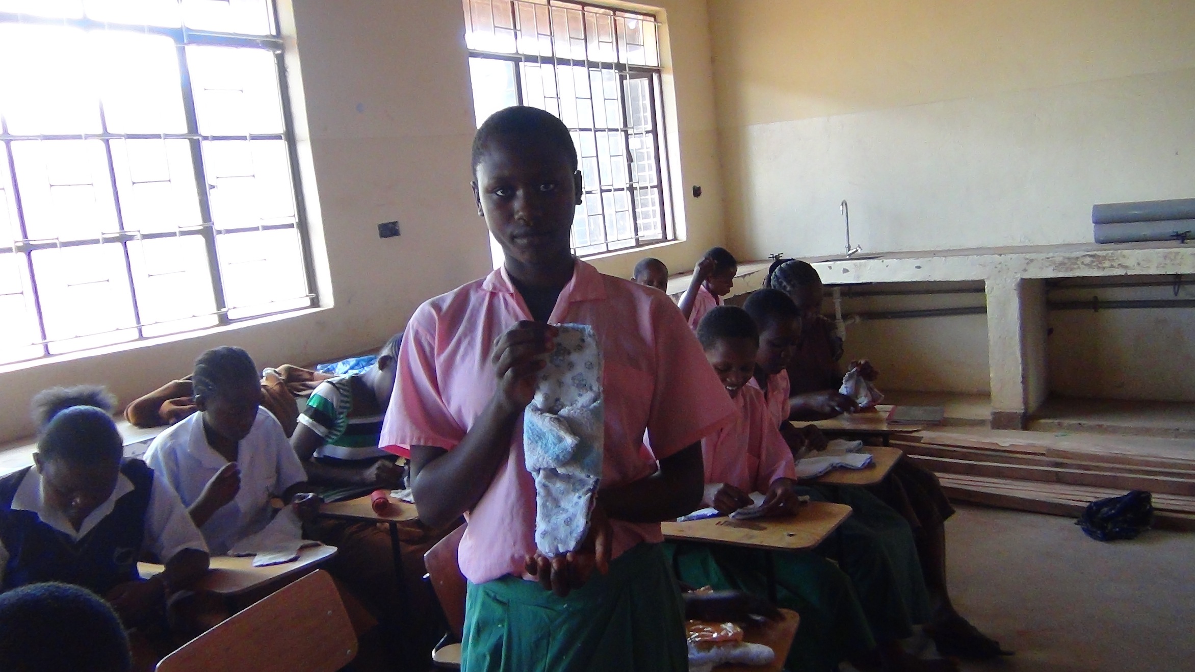 A student from Itinyi Primary School posing with the sanitary towel that she knit
